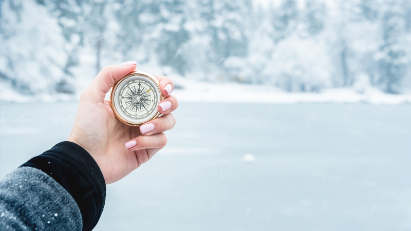A woman holding a compass during a cold winter day